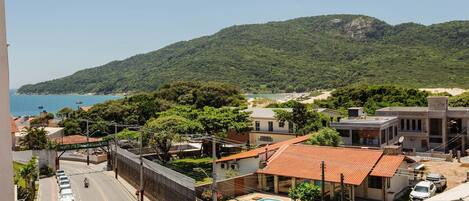 Un área residencial con piscina, una calle con coches estacionados y vistas al mar y las colinas.