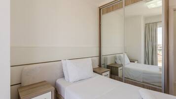 Habitación de hotel con cama, mesita de noche, espejo y armario.