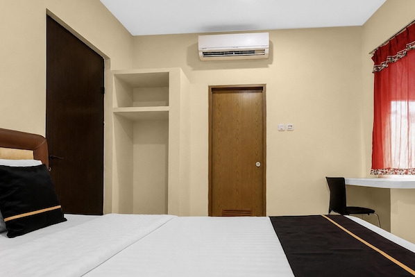 A room with a bed, a wardrobe, a door, an air conditioning unit, and a chair.