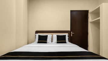 A single bed with a wooden headboard, white and black bedding, and a door to the right.