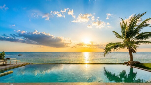 Una piscina con vista al océano y al atardecer.