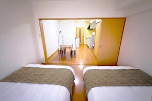 Une chambre avec deux lits, un plancher en bois, une kitchenette et un coin repas.