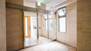 A modern interior with a glass partition, tiled flooring, and a ceiling with a grid pattern.