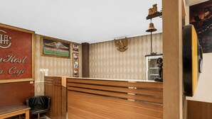 A reception desk with a wooden finish, a black leather chair, and a wall-mounted telephone. - Hotel O Kosta Living - Standard Single (Palembang)