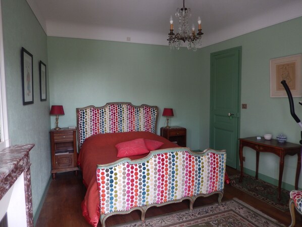 A bedroom with a bed, dresser, nightstand, and a chandelier.