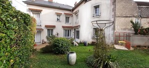 A two-story building with a well-maintained garden, a basketball hoop, and a greenhouse.