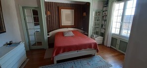 A bedroom with a bed, bedside tables, a wardrobe, and a window with a view.