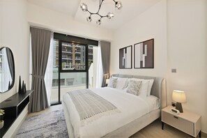 Ein modernes Hotelzimmer mit einem großen Bett, einem Nachttisch mit Lampe, einem Spiegel und Blick ins Freie.