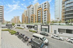 Ein modernes Gebäude mit mehreren Stockwerken, ein Parkplatz mit Motorrädern und Autos sowie ein klarer Himmel.