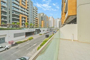 A modern urban street with high-rise buildings, a clear sky, and a pedestrian walkway. - Bloomfields 2BR in Azizi Riviera 43 - Meydan (Dubai)