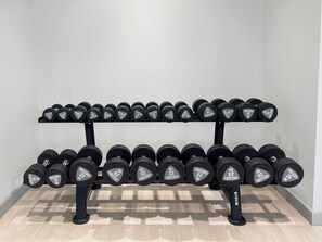 A rack of dumbbells with weight markings, arranged in two rows. - Bloomfields 2BR in Azizi Riviera 43 - Meydan (Dubai)