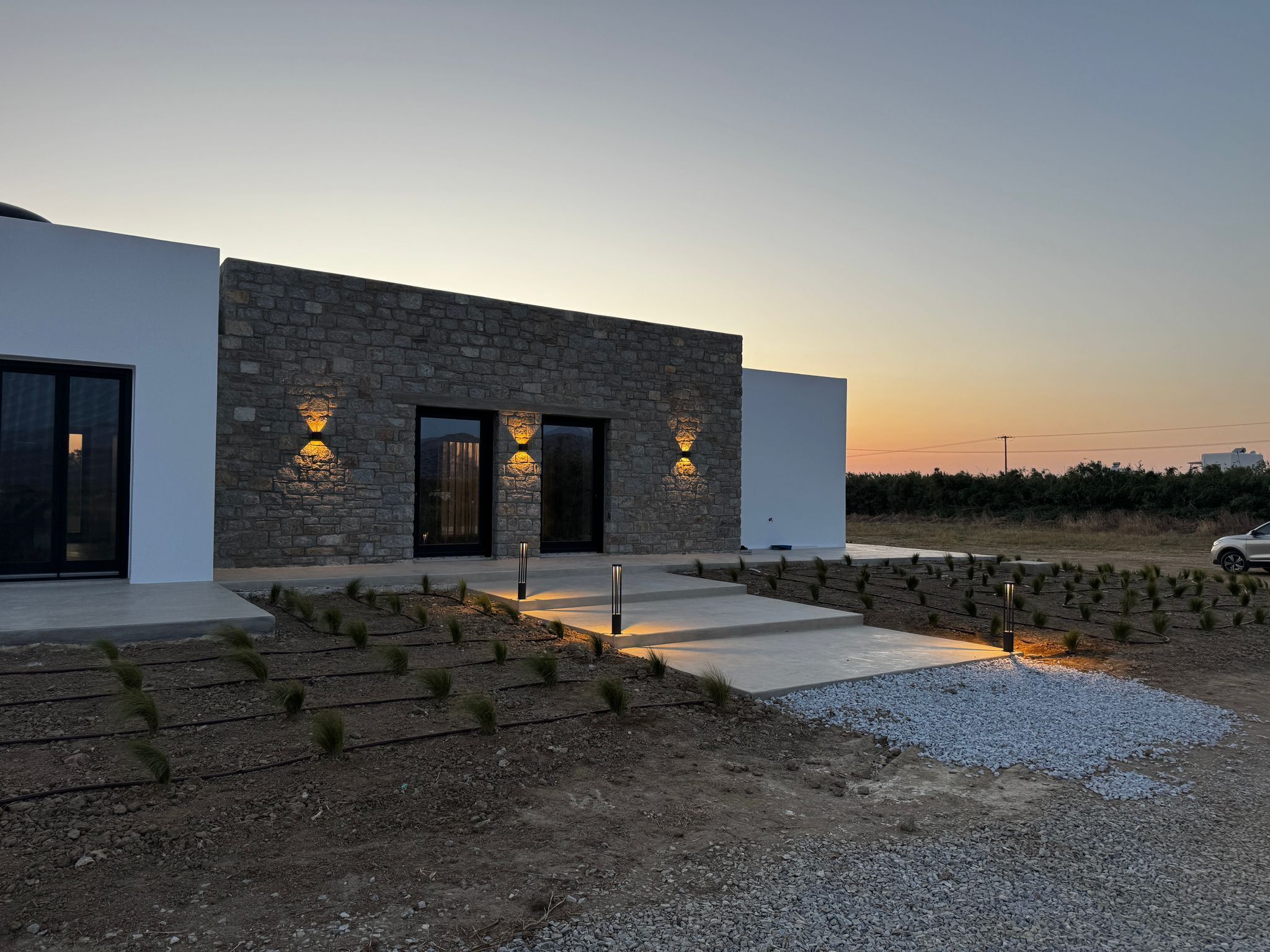 A modern building with a stone facade, large windows, and outdoor lighting.