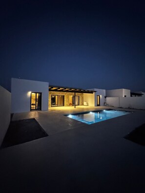 A modern outdoor pool area with a covered patio and a stone building. - Private 3-bedroom Cycladic villa with pool in Naxos (Naxos)