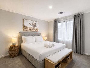 A hotel room with a large bed, two bedside lamps, a wall-mounted artwork, and a window with curtains. - Spacious 4-Bed Retreat Near Meadow Springs (Meadow Springs)