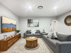 Ein modernes Wohnzimmer mit einem grauen Sofa, einem Holztisch und Bildern an den Wänden.