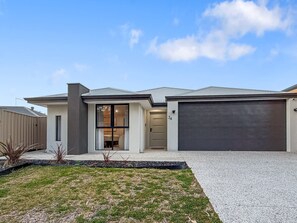 Ein modernes, zweistöckiges Haus mit Garage, Eingangstür und gepflegtem Rasen.