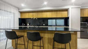 Uma cozinha moderna com uma ilha central, banquetas e vista para a área de estar adjacente.