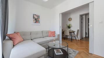 Un saló modern amb un sofà seccional gris, una taula de centre de vidre i una obra d'art emmarcada a la paret.