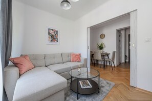 A modern living room with a grey sectional sofa, a glass coffee table, and a framed artwork on the wall. - Lumina 3-room Apart near Park & Balcony (Warszawa)