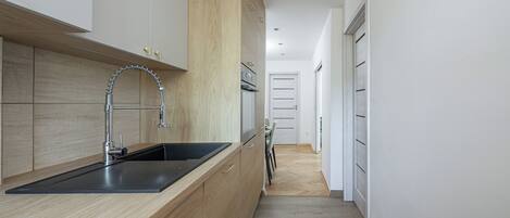 A modern kitchen with a black sink, wooden cabinets, and a stainless steel faucet.