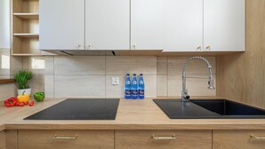 Una cocina moderna con placa de inducción negra, un lavamanos de acero inoxidable y armarios de madera.