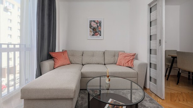 Una sala de estar moderna con un sofá seccional gris, una mesa de centro de vidrio y un cuadro en la pared.