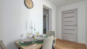 Comedor con una mesa de madera dispuesta para dos personas, dos velas y dos copas de vino blanco.