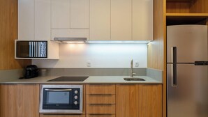 Eine kompakte Küche mit Einbauofen, Kaffeemaschine, Spüle und Kühlschrank.