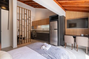 Ein modernes Schlafzimmer mit Bett, Schreibtisch und einer Küchenzeile.