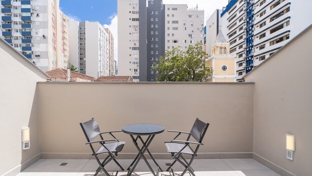 A balcony with two chairs and a small table, overlooking a cityscape with tall buildings. - Studio With Private Balcony in Floripa Cma0201 (Florianópolis)
