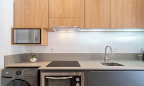 A modern kitchen with wooden cabinets, a built-in microwave, a stainless steel sink, and a dishwasher. - Studio With Private Balcony in Floripa Cma0201 (Florianópolis)