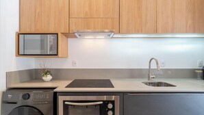 A modern kitchen with wooden cabinets, a built-in microwave, stainless steel appliances, and a sink. - Studio With Private Balcony in Floripa Cma0201 (Florianópolis)
