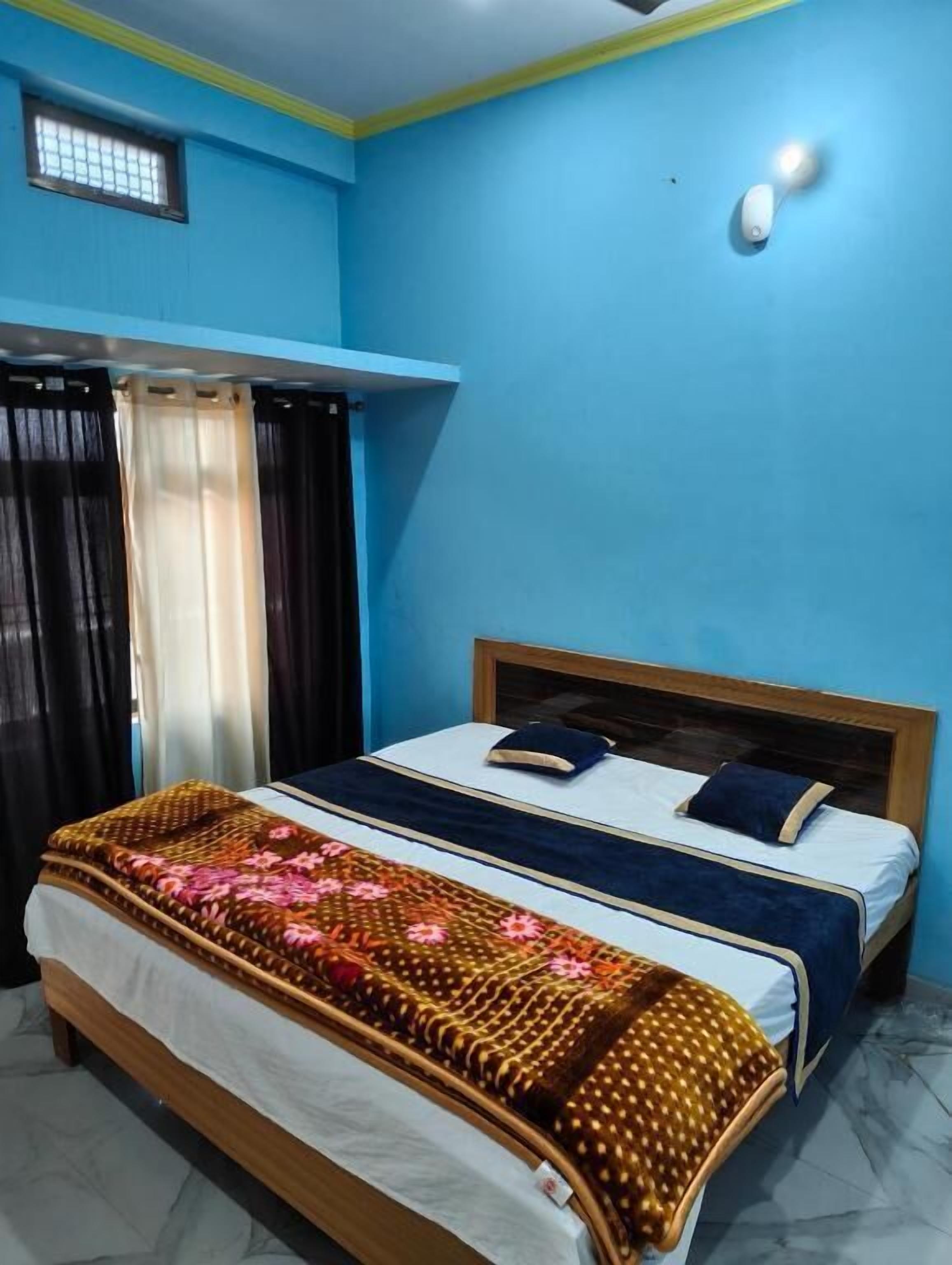 Une chambre à coucher avec un lit, des rideaux, une table de chevet et un luminaire fixé au mur.