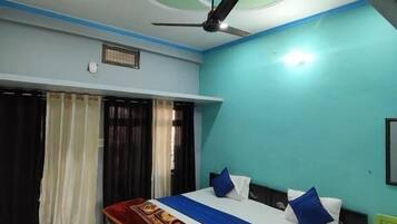 Un dormitorio con cama, ventilador de techo y ventana con cortinas.