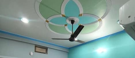 A bedroom with a bed, a ceiling fan, and a window with curtains.