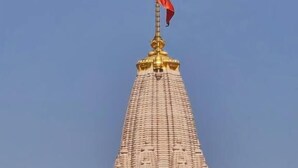 Une grande structure conique, surmontée d’un drapeau, et entourée d’arbres.