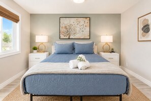 Ein Schlafzimmer mit einem großen Bett, zwei Nachttischen, einem Fenster und Bildern an den Wänden.