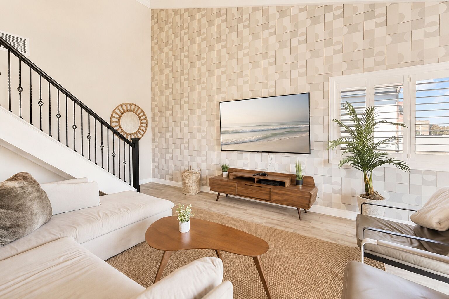 Una sala de estar moderna con una escalera, un televisor de pantalla plana, una mesa de centro de madera y una planta grande en maceta.