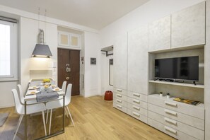 A modern kitchen with white cabinetry, a dining table set for four, and a flat-screen TV mounted on the wall. - Sabotino, 16 – Milan Vibes (Milano)