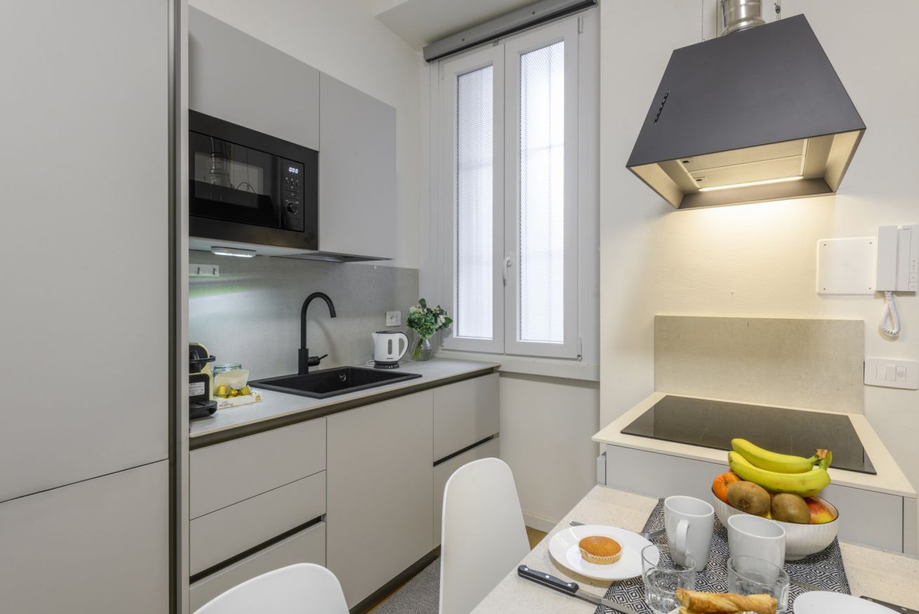 Une cuisine compacte équipée d’un four à micro-ondes, d’un évier et d’un petit coin repas avec une table dressée pour deux personnes.