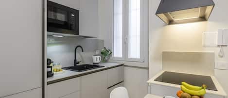 Une cuisine compacte équipée d’un four à micro-ondes, d’un évier et d’un petit coin repas avec une table dressée pour deux personnes.