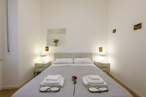 A hotel room with a bed, two bedside tables, a nightstand, a mirror, and a wall-mounted shelf with a vase. - Sabotino, 16 – Milan Vibes (Milano)
