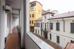 A narrow corridor with a tiled floor, leading to a building with a balcony. - Sabotino, 16 – Milan Vibes (Milano)