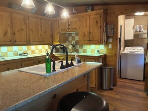 A kitchen with wooden cabinets, a granite countertop, a sink, a stainless steel trash can, and a white refrigerator. - Gated property - 3 bedroom 2 bath plenty of room for your toys (Kingston)