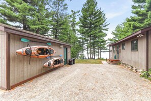 A gravel driveway leading to a building with kayaks mounted on the wall. - Lake Petenwell Hideaway with Private Dock & Kayaks (Arkdale)