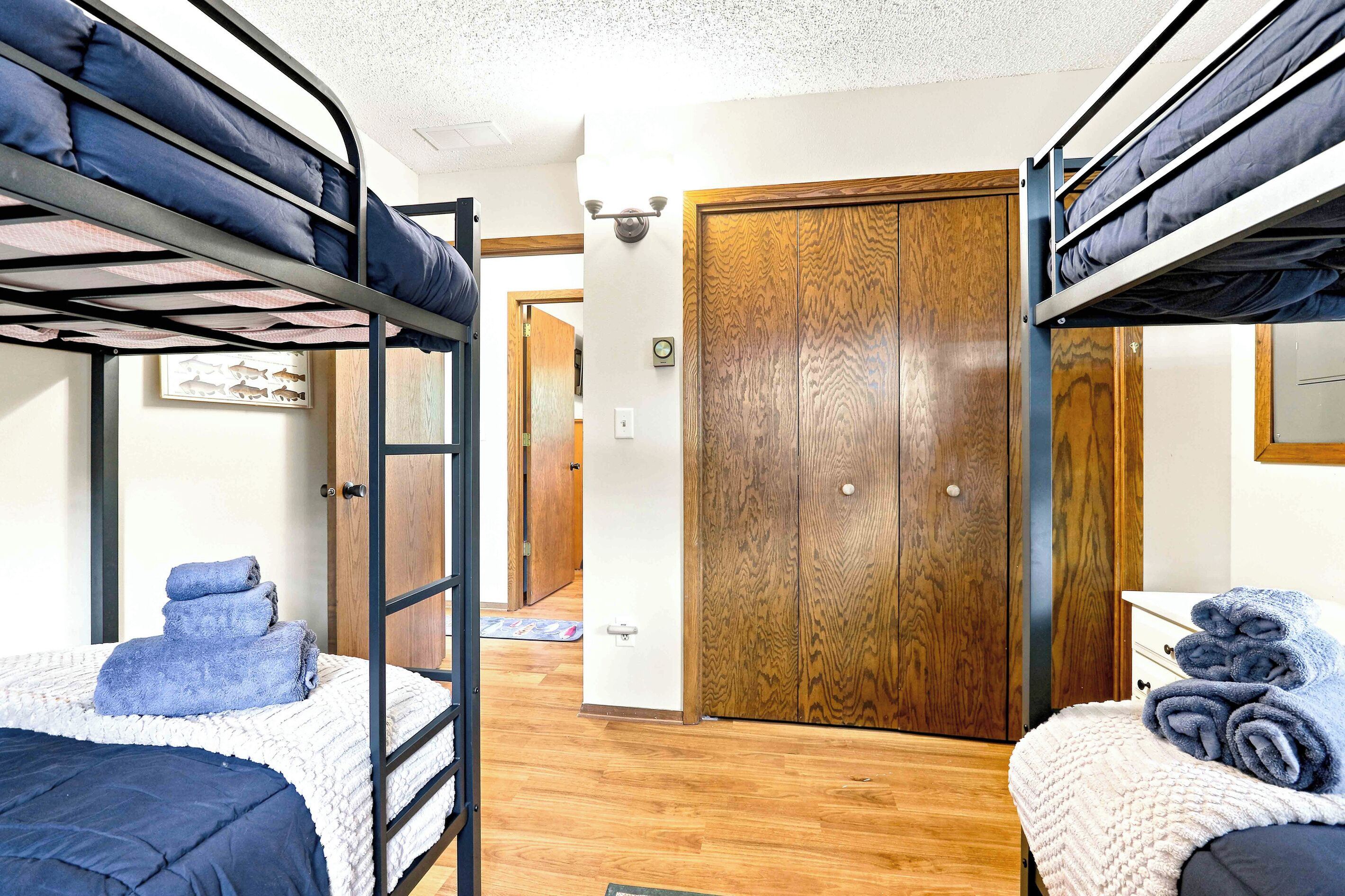 A dormitory room with bunk beds, a wooden door, and a small hallway.