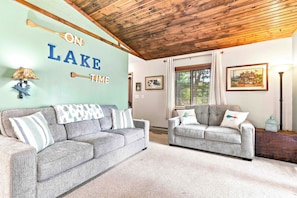 A living room with two grey sofas, a wooden ceiling, a wall with 'ON LAKE TIME' text, and a lamp. - Lake Petenwell Hideaway with Private Dock & Kayaks (Arkdale)