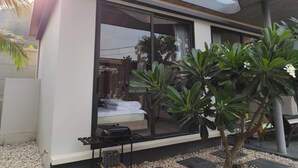 Una casa moderna con un amplio ventanal, un pequeño patio con plantas y techo de madera.