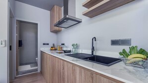 Una cocina moderna con encimera de madera, pileta negra y campana extractora de acero inoxidable.