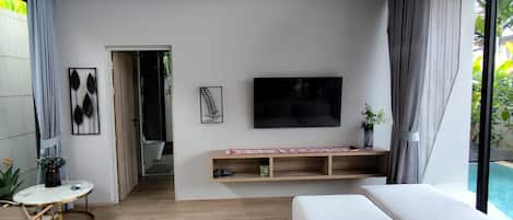 A modern living room with a large sofa, a flat-screen TV, and a wooden ceiling.